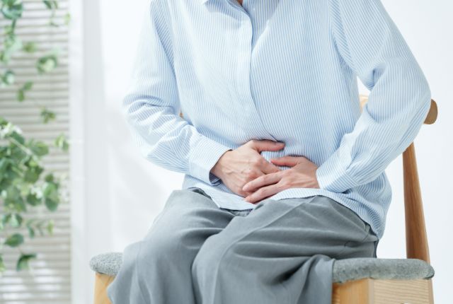 手でお腹を押さえている女性