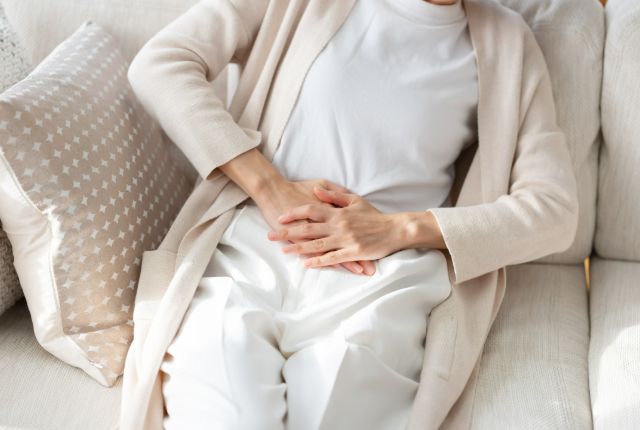 腹部を手で押さえる女性